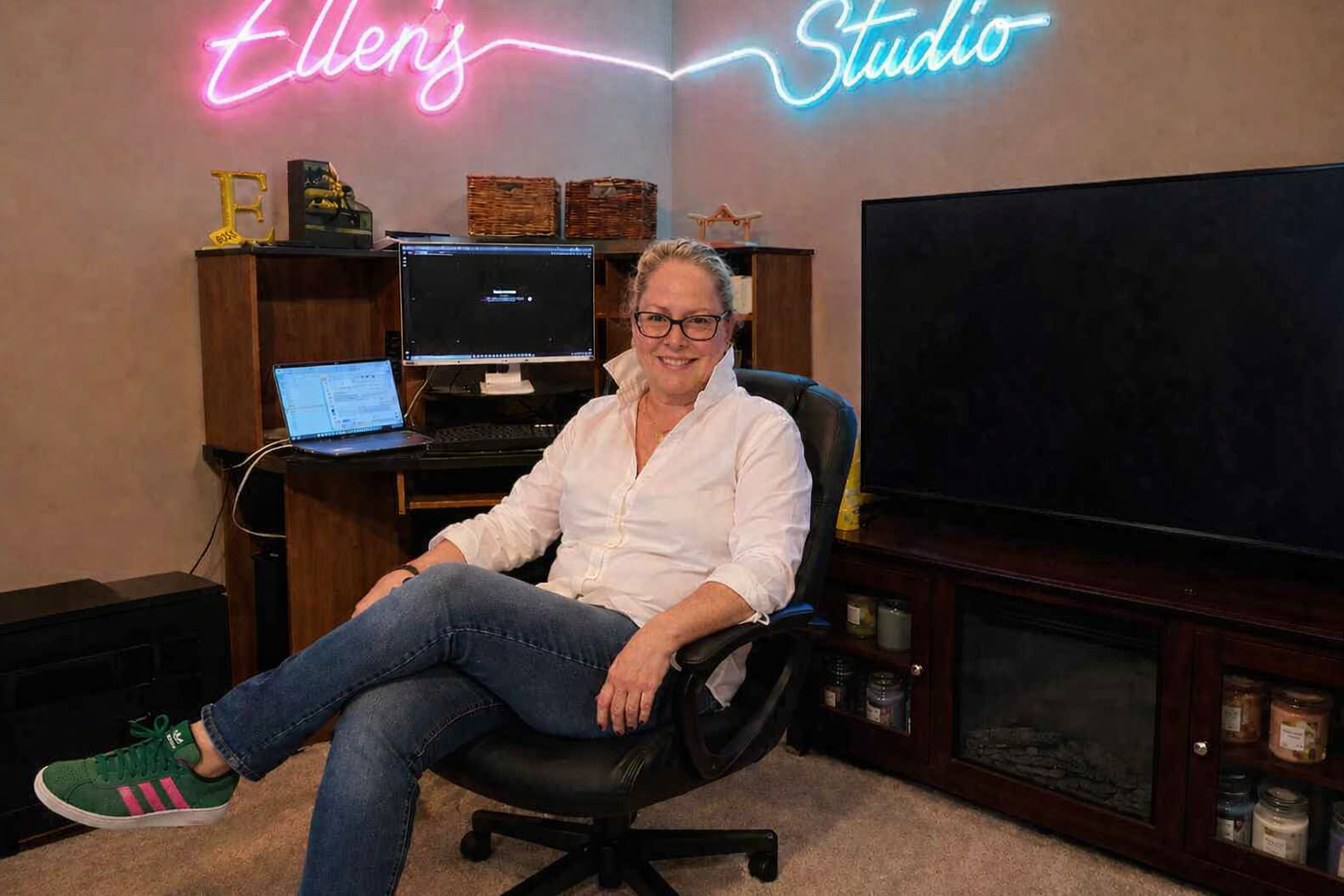 Ellen Shinault seated in her creative studio under an 'Ellen's Studio' neon sign